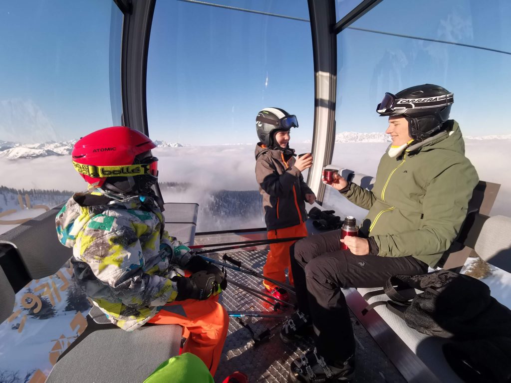 Eine Familie genießt heißen Tee in der Panorama-Gondel beim Skifahren in Kleinarl – Komfort und Genuss im Winterurlaub am Schwabhof.